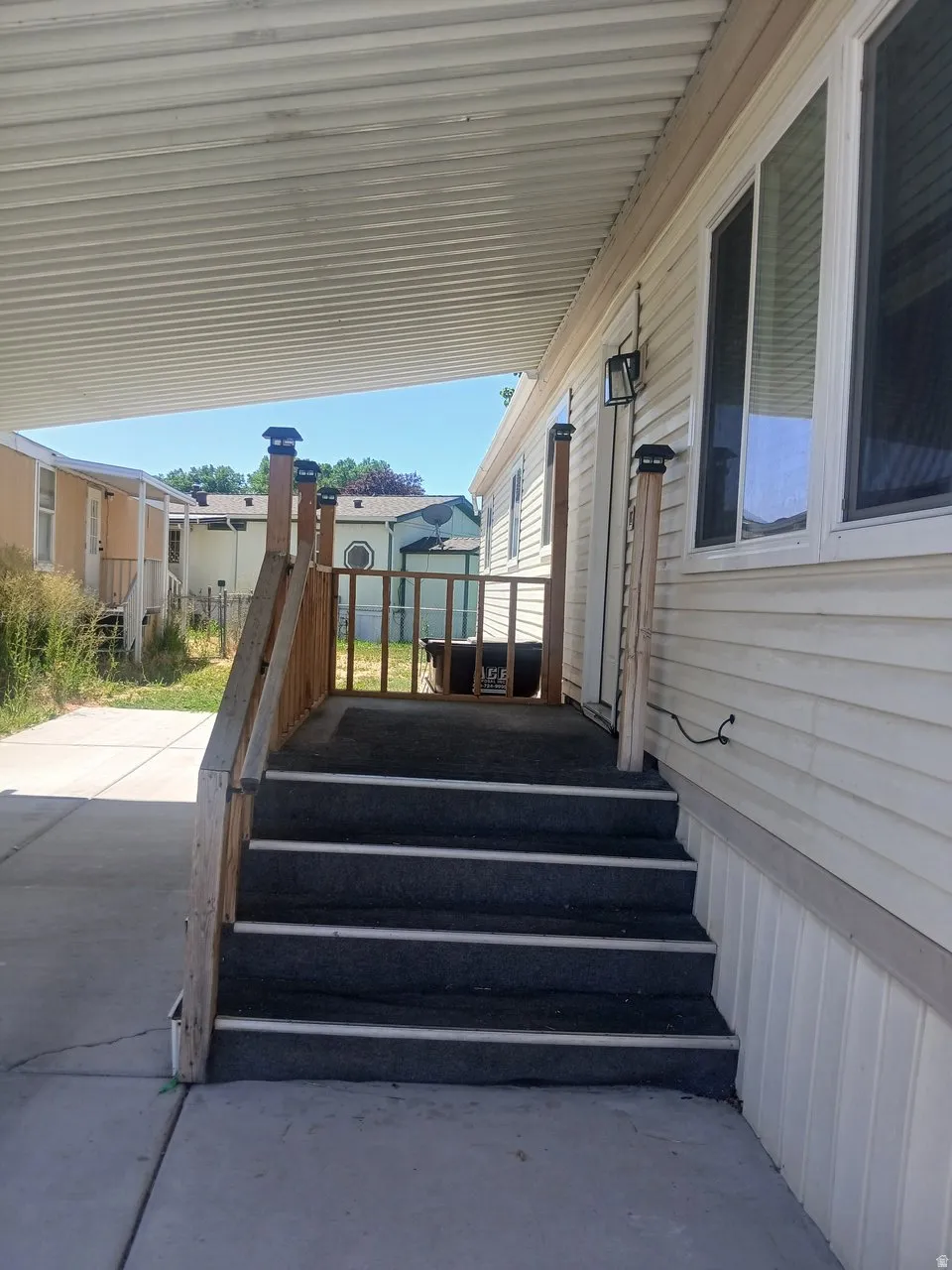 Covered entry featuring wood railings and exterior lighting