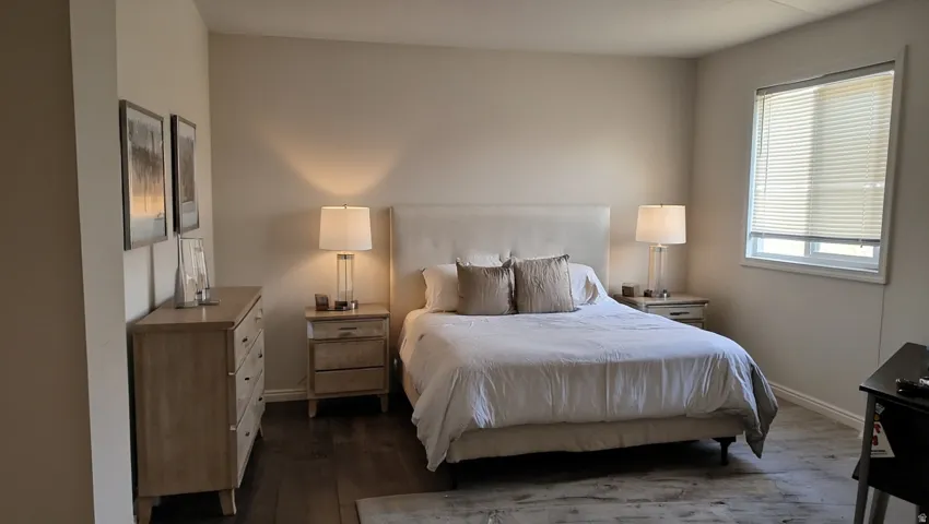 Spacious room featuring wood-finish flooring, a large window with blinds, and neutral wall tones