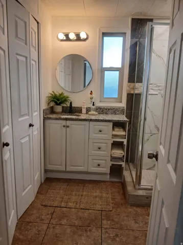 White vanity with integrated storage, granite-style countertop, and vessel sink