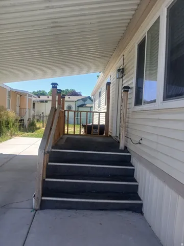 Covered entry featuring wood railings and exterior lighting