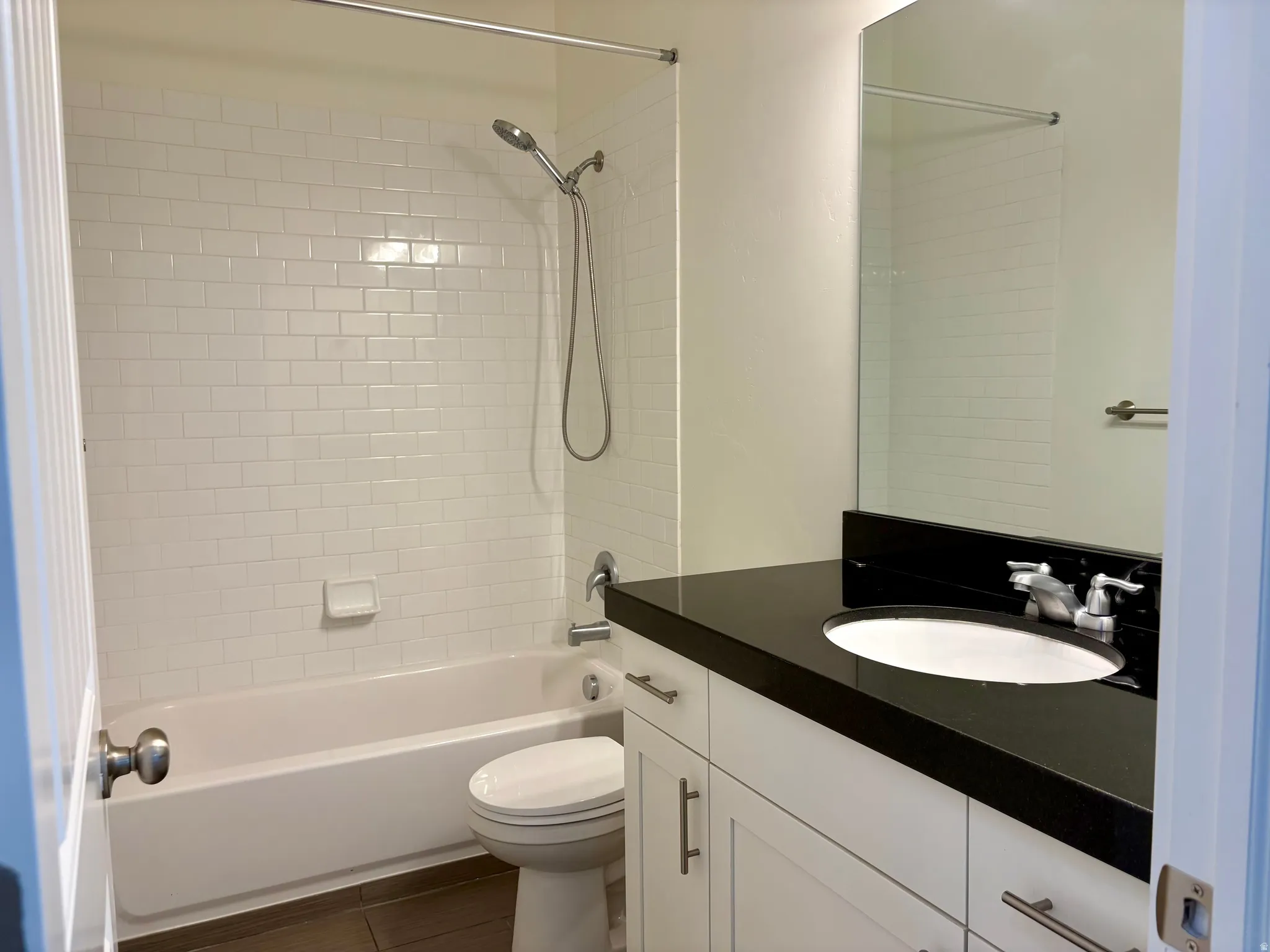 White subway tile shower surround with a handheld shower fixture