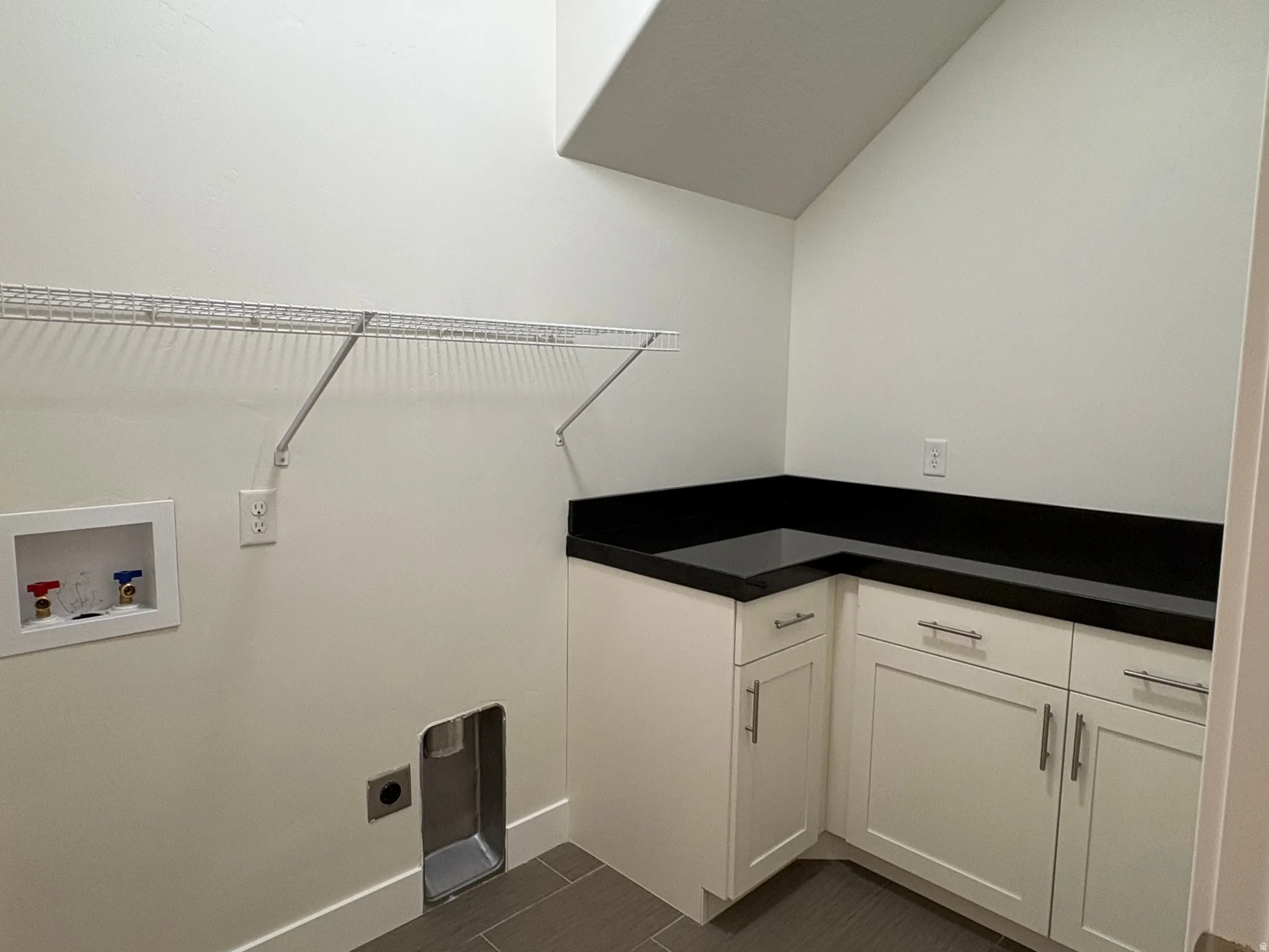 White cabinetry with dark countertops, tile flooring, and integrated wall shelving