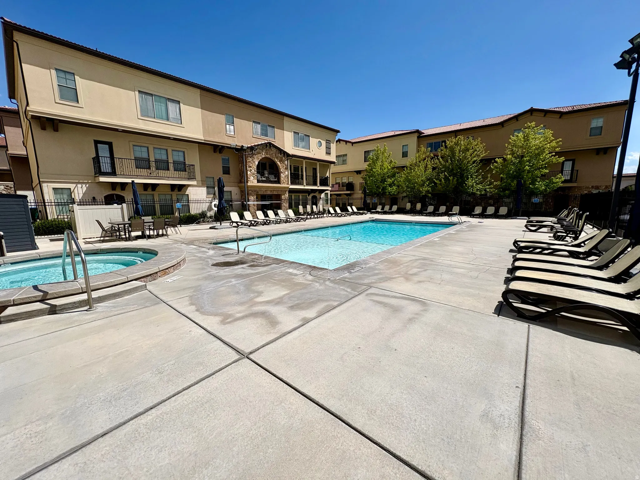 Expansive outdoor pool area featuring a rectangular swimming pool, an elevated spa, and a concrete patio