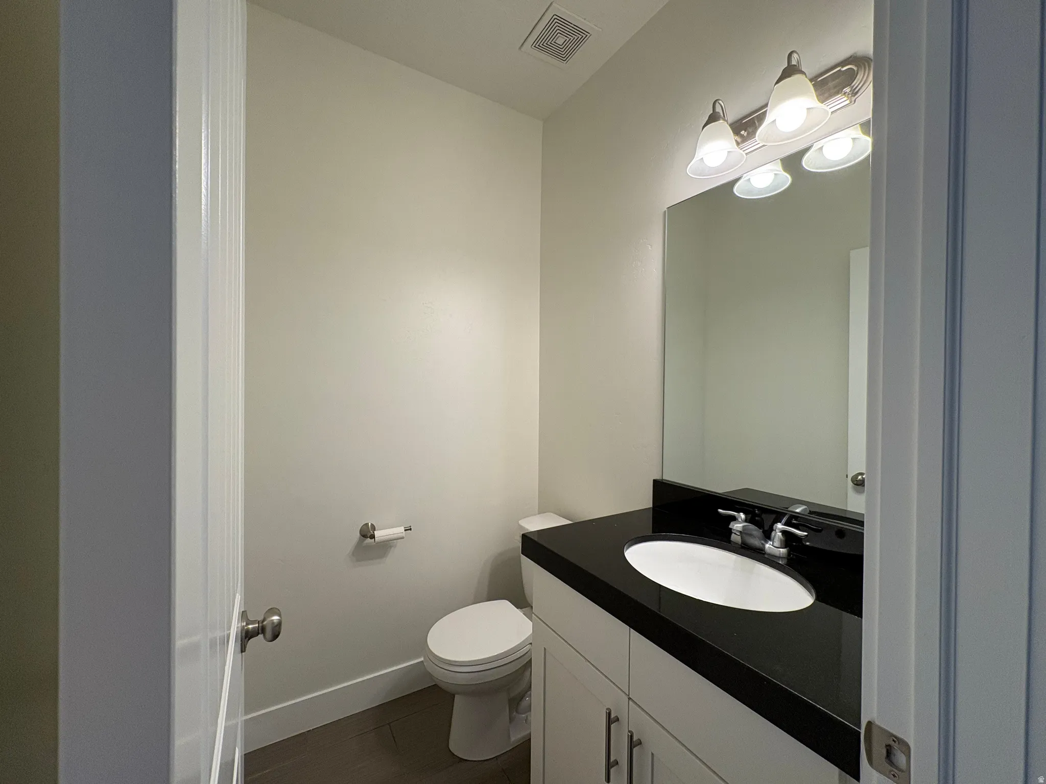 Vanity with a dark countertop and undermount sink, brushed nickel faucet, and a wall-mounted mirror