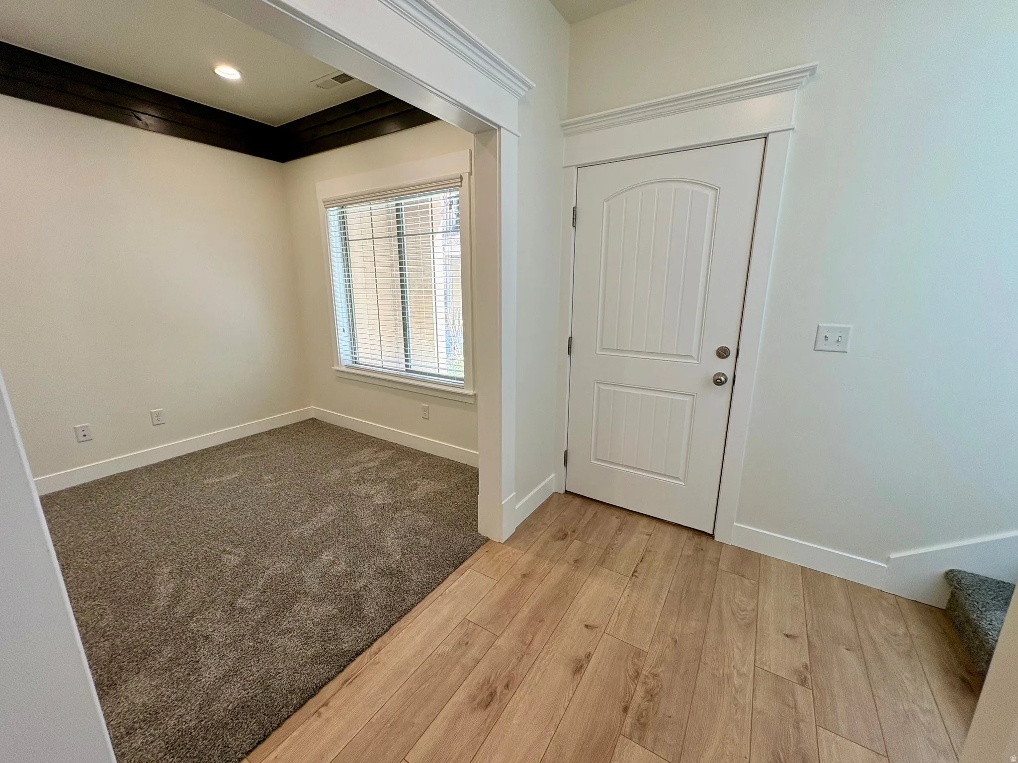 Wood-finish flooring, recessed lighting, white trim, and a paneled interior door