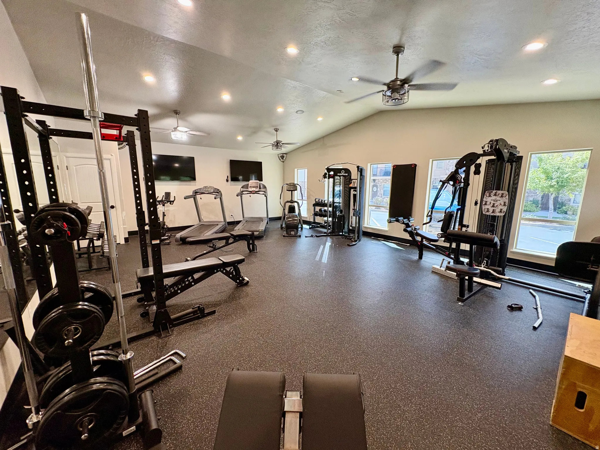 Spacious fitness room featuring a vaulted ceiling with recessed lighting, ceiling fans, and rubberized flooring