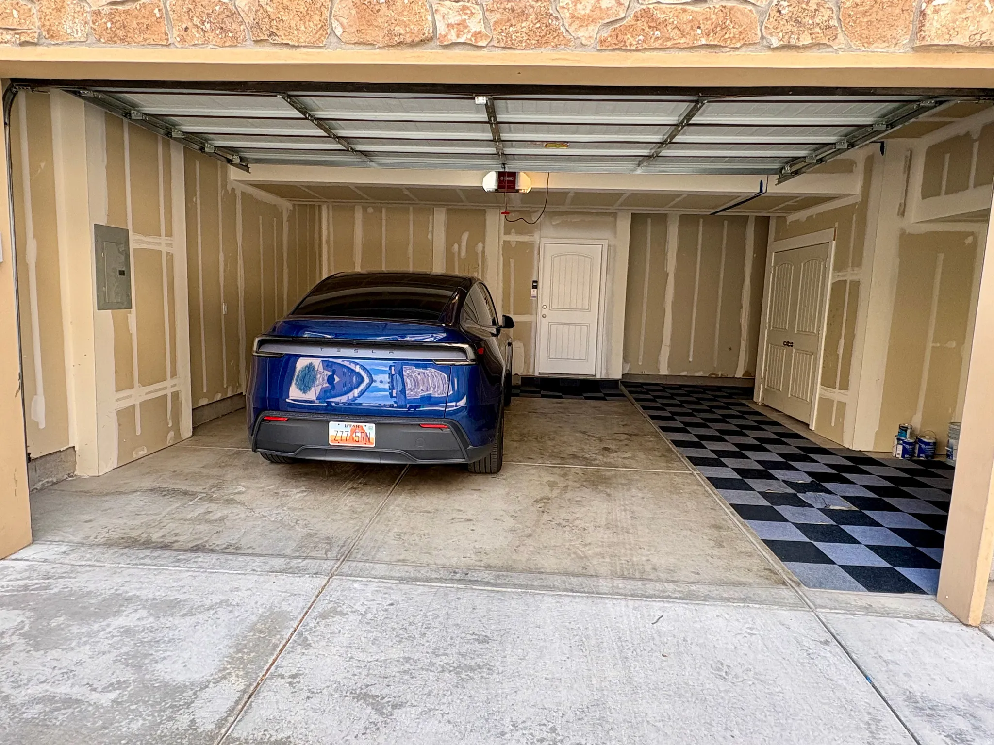 Attached garage featuring a concrete floor, stone facade, and interior access doors