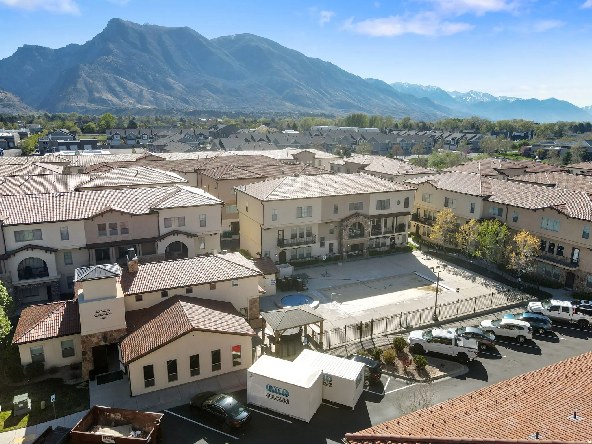 Gated community courtyard featuring multiple residences with varied architectural styles, metal roofing, arched entryways, and a central parking area