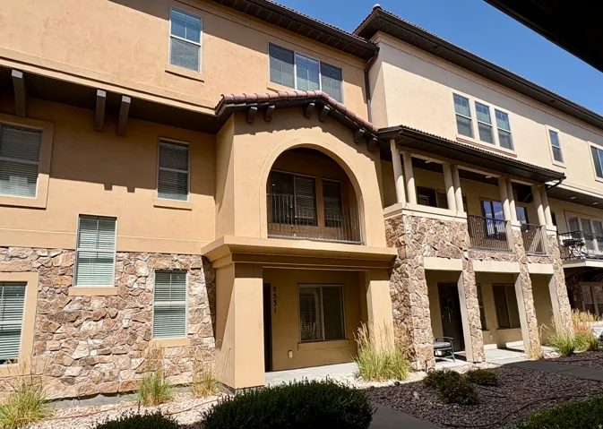 Exterior featuring stucco finish, stone accents, multiple balconies with wrought iron railings, and a tile roof detail