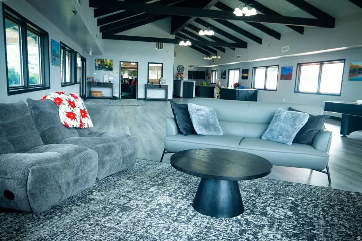 Vaulted ceiling with exposed wood beams, wood-finish flooring, recessed lighting, multiple windows, and a built-in counter area