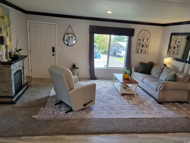 Bright and spacious living room featuring hardwood-finish flooring, a wood-burning fireplace with brick surround, and abundant natural light from sliding glass doors
