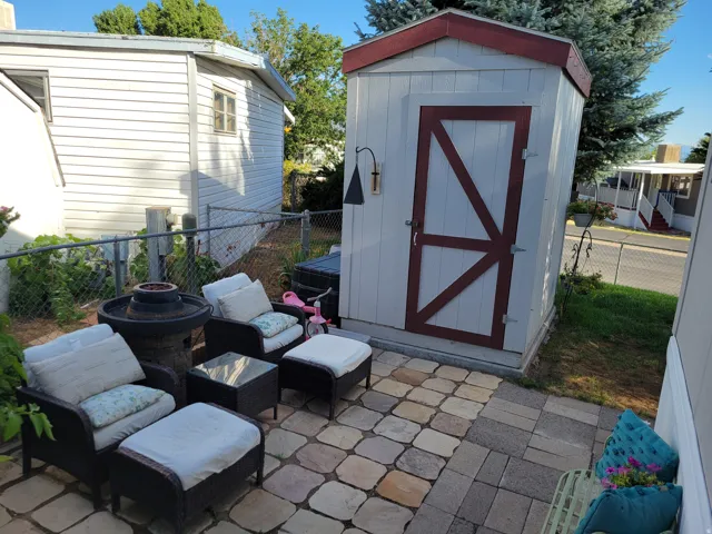 Paver patio featuring varied stone colors, accompanied by a detached storage shed with a contrasting trim door