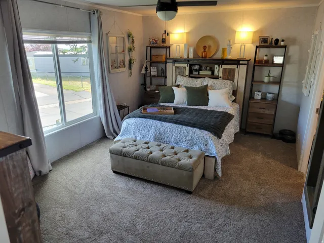 Carpeted flooring throughout, featuring a window with natural light, and a ceiling fan with integrated lighting