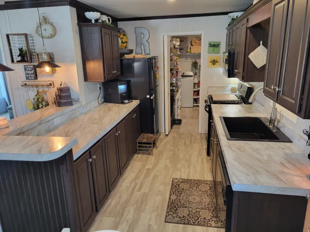 Kitchen featuring rich wood-finish cabinetry, light-toned countertops, and wood-finish flooring