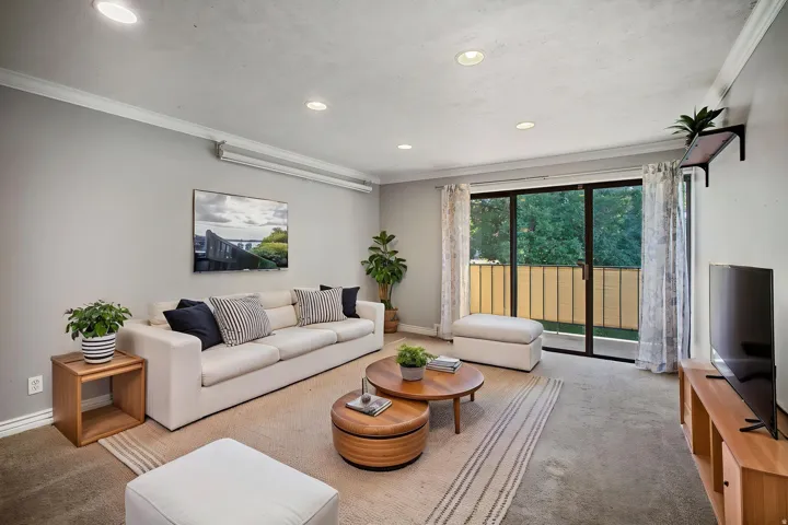 Recessed lighting illuminates the living area, featuring crown molding and light gray wall tones