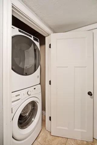 Stackable laundry appliances with a front-loading washing machine and dryer, finished with tiled flooring