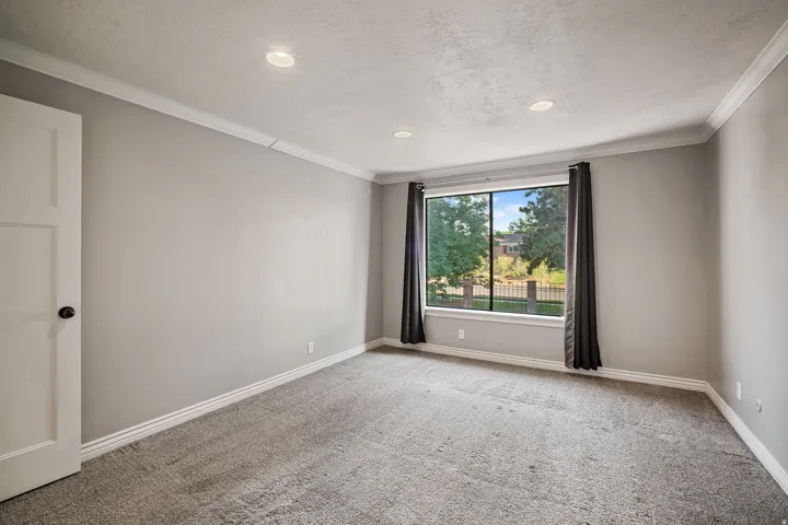 Recessed lighting, crown molding, gray carpet, and a large window with white trim