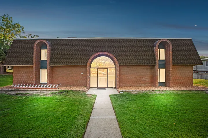 Brick exterior featuring an arched glass entry and multiple arched window elements