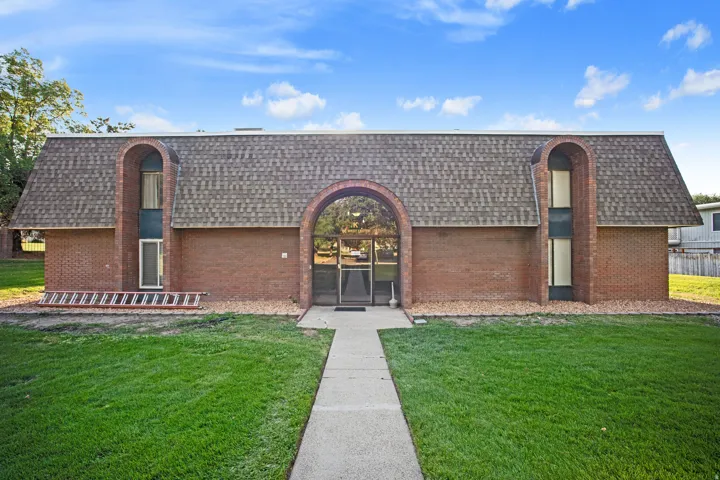 Brick exterior with an arched entryway and asphalt shingle roofing