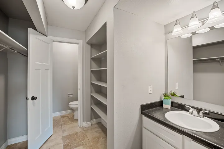 Vanity with a built-in sink, dark countertop, and a large mirror
