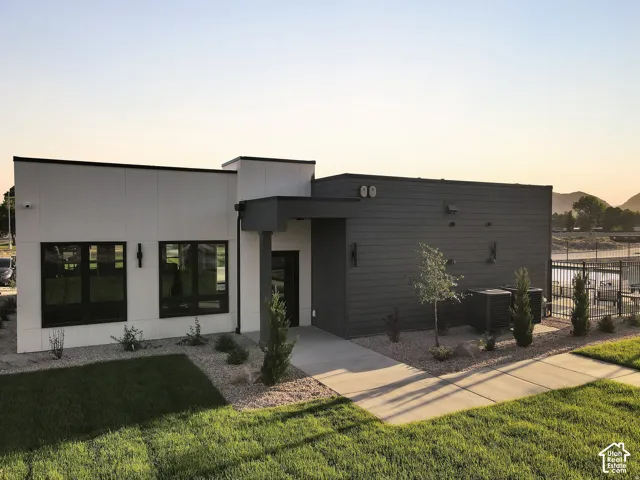 Modern architectural design featuring a clean-lined facade with mixed material finishes—white and charcoal exterior cladding—complemented by expansive black-framed windows and glass doors