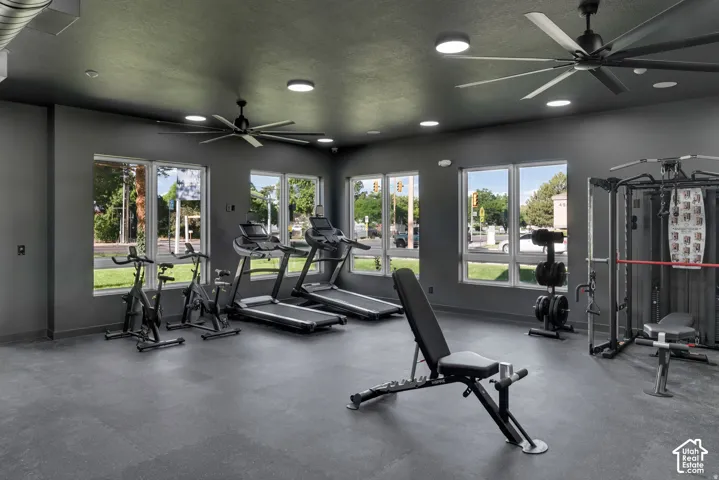Expansive fitness area with resilient flooring, multiple large windows, recessed lighting, and dual ceiling fans