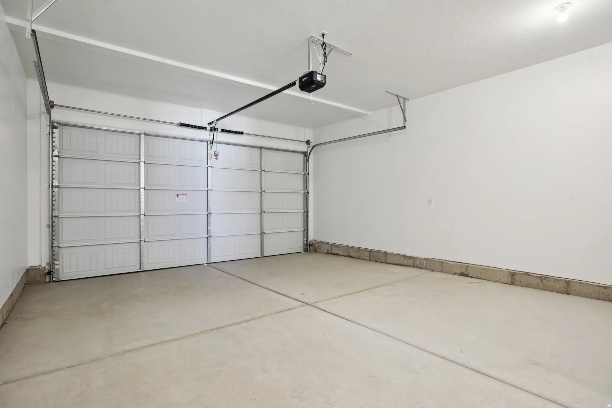 Two-car garage featuring a sectional overhead door and an automatic opener