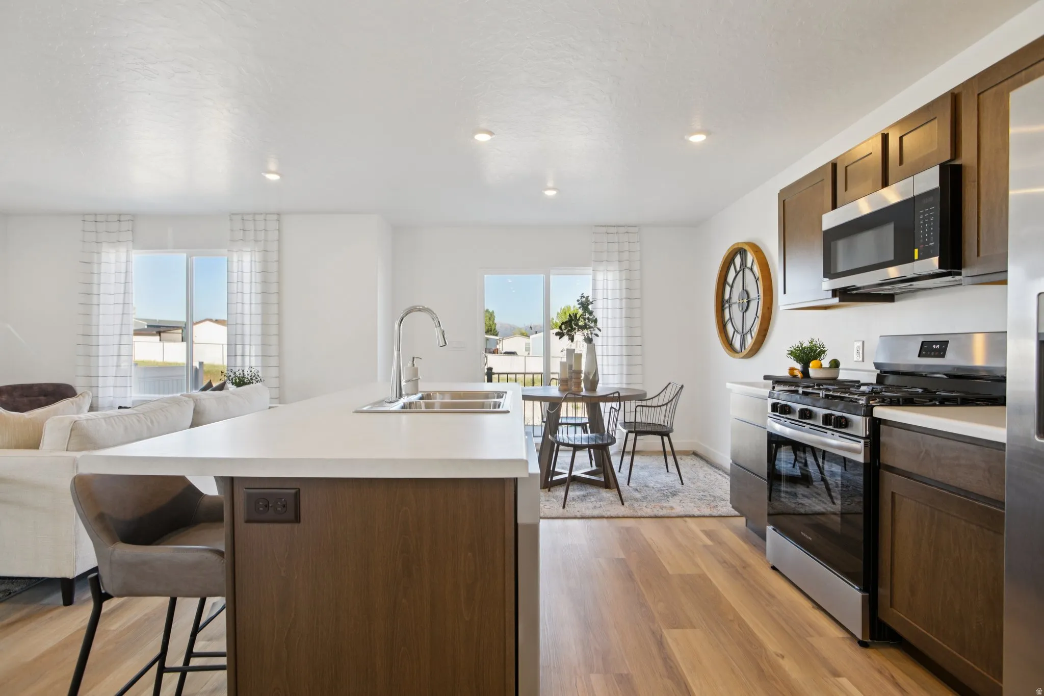 Open-concept living space with wood-finish flooring, recessed lighting, and white walls