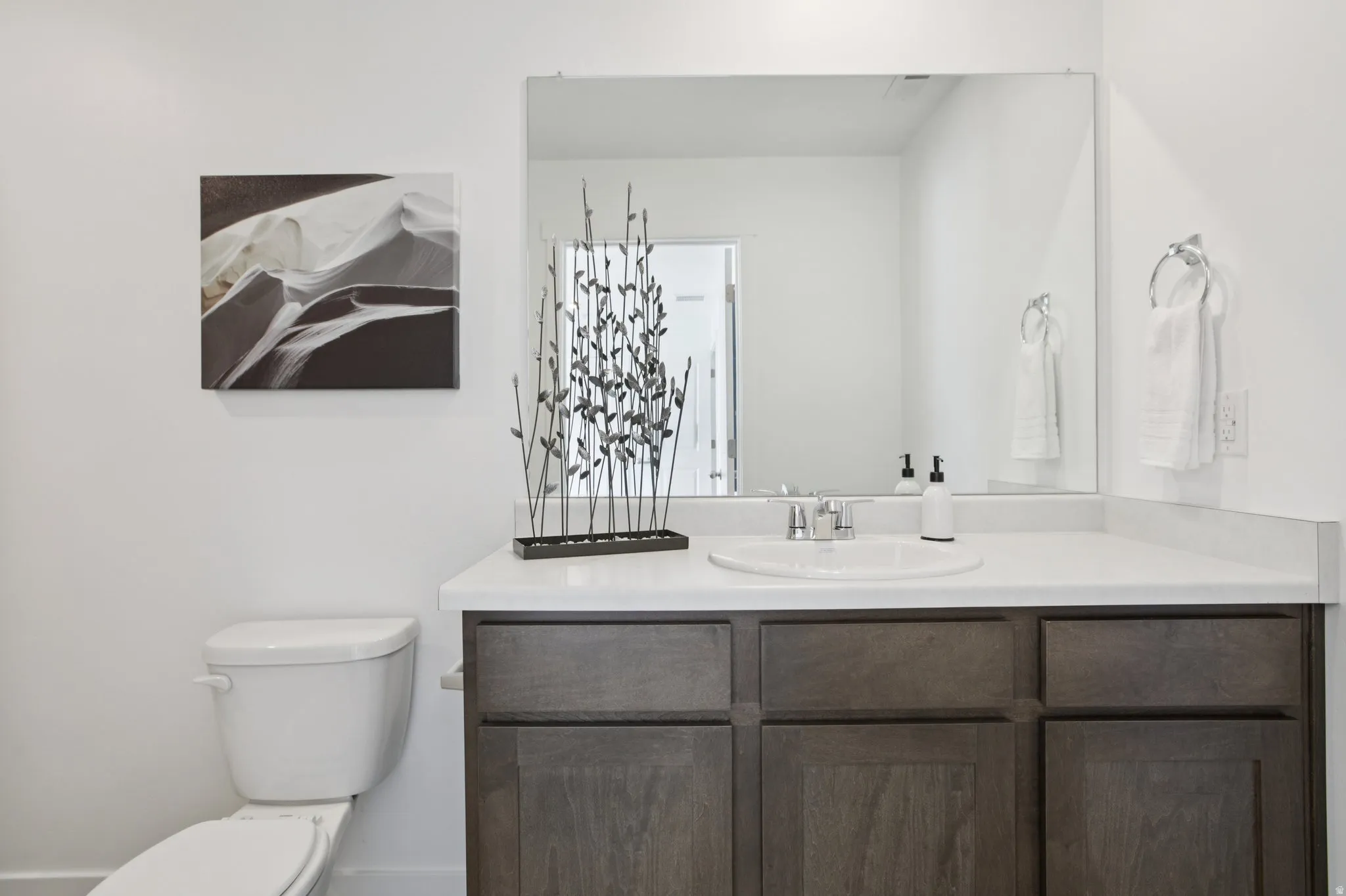 White countertop with an integrated sink and a large vanity mirror
