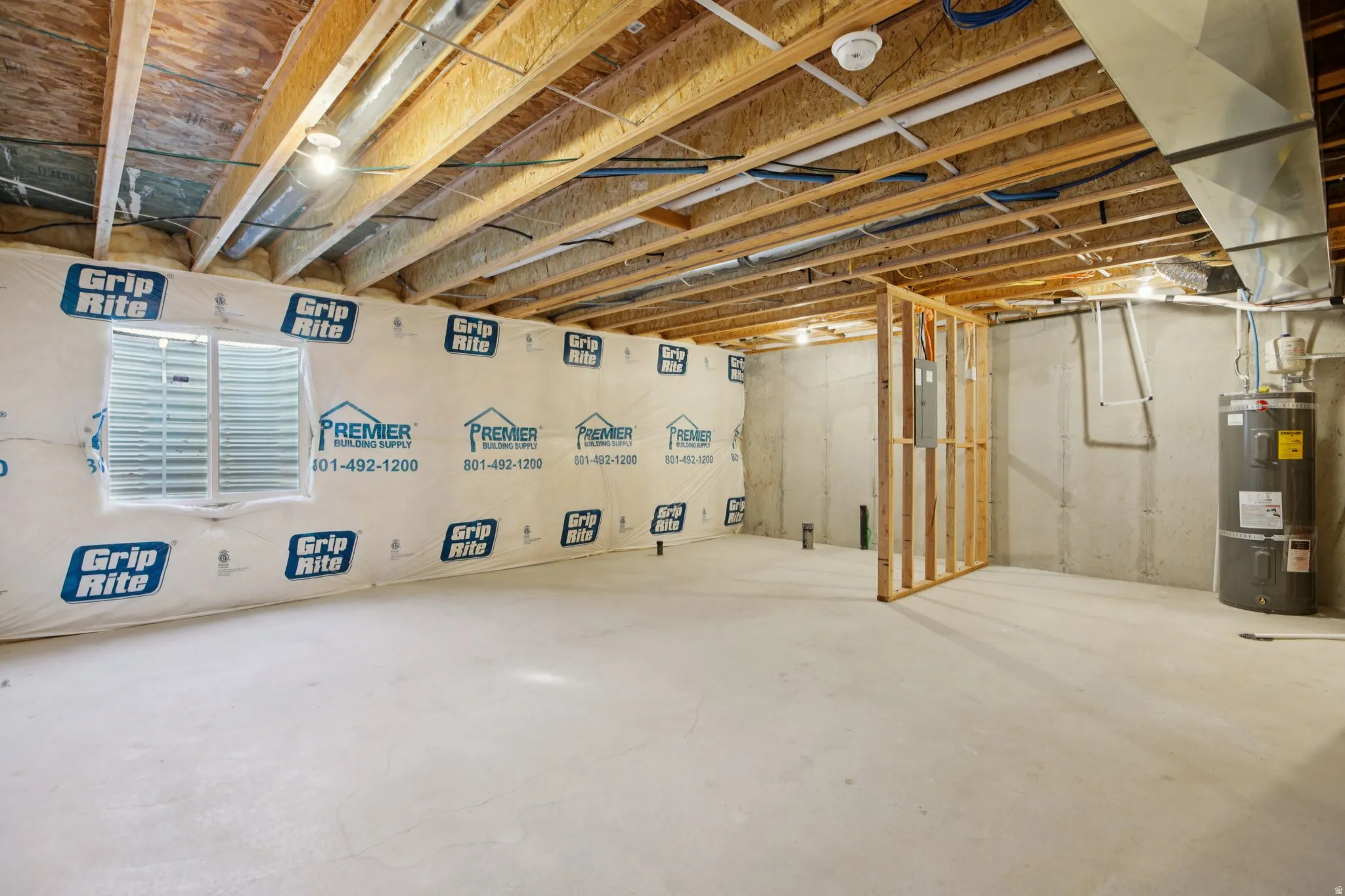 Unfinished basement with exposed ceiling joists, concrete flooring, and a single window