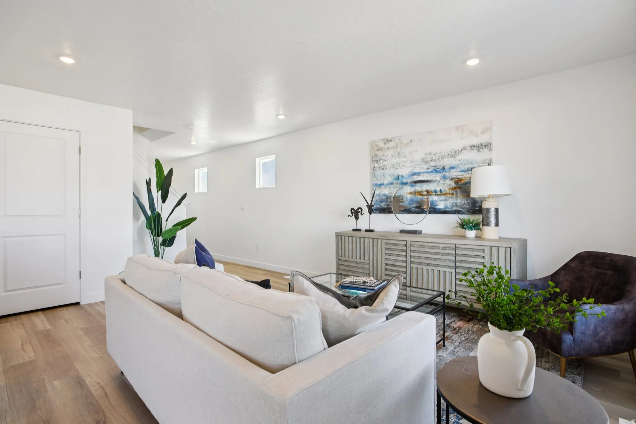 Recessed lighting illuminates the living area with wood-finish flooring