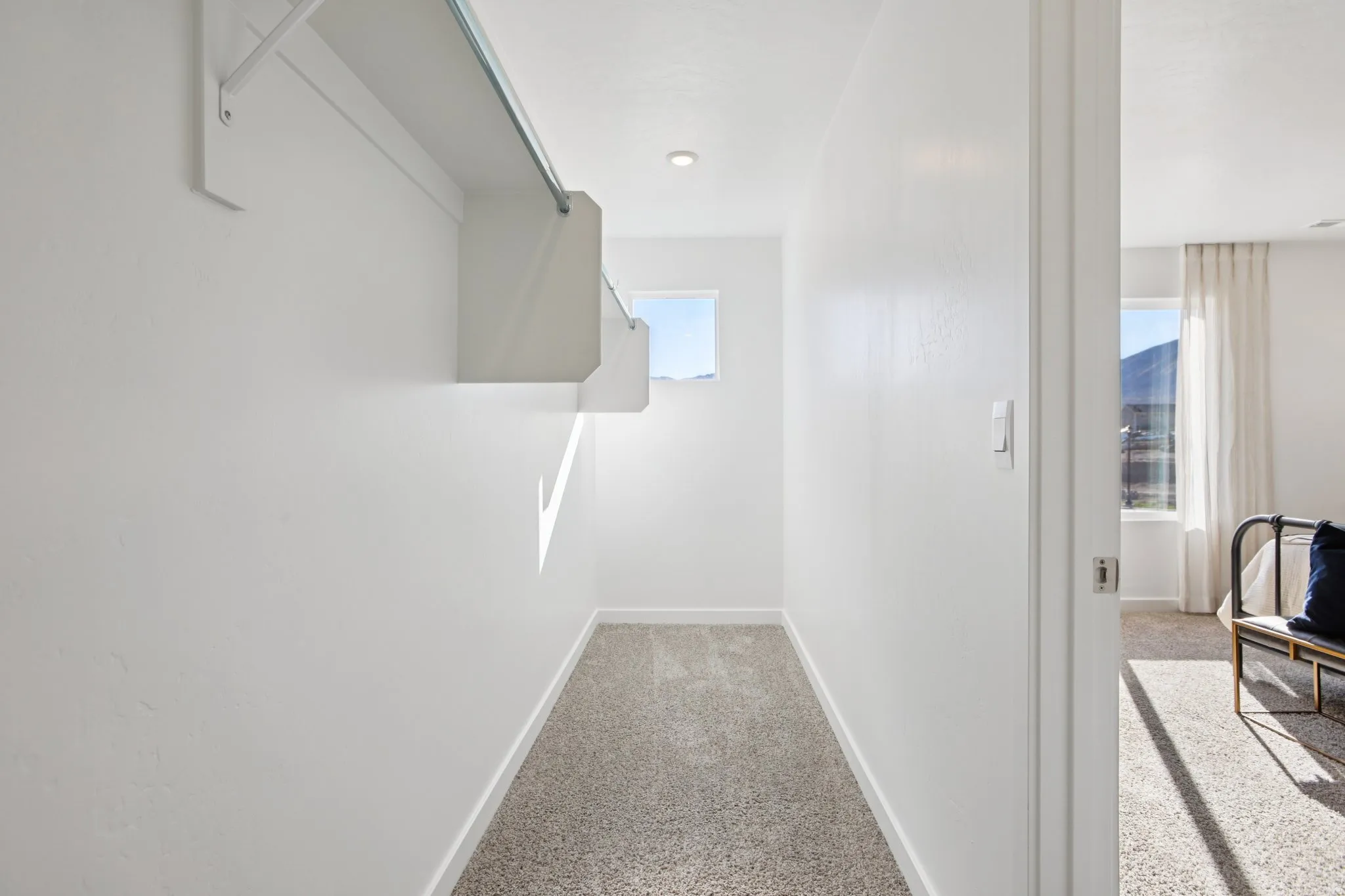 Walk-in closet with built-in shelving, hanging rod, and window