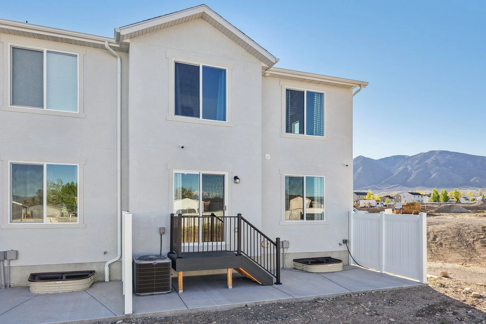 Modern two-story residence featuring a clean white exterior with multiple windows and dark-framed glazing