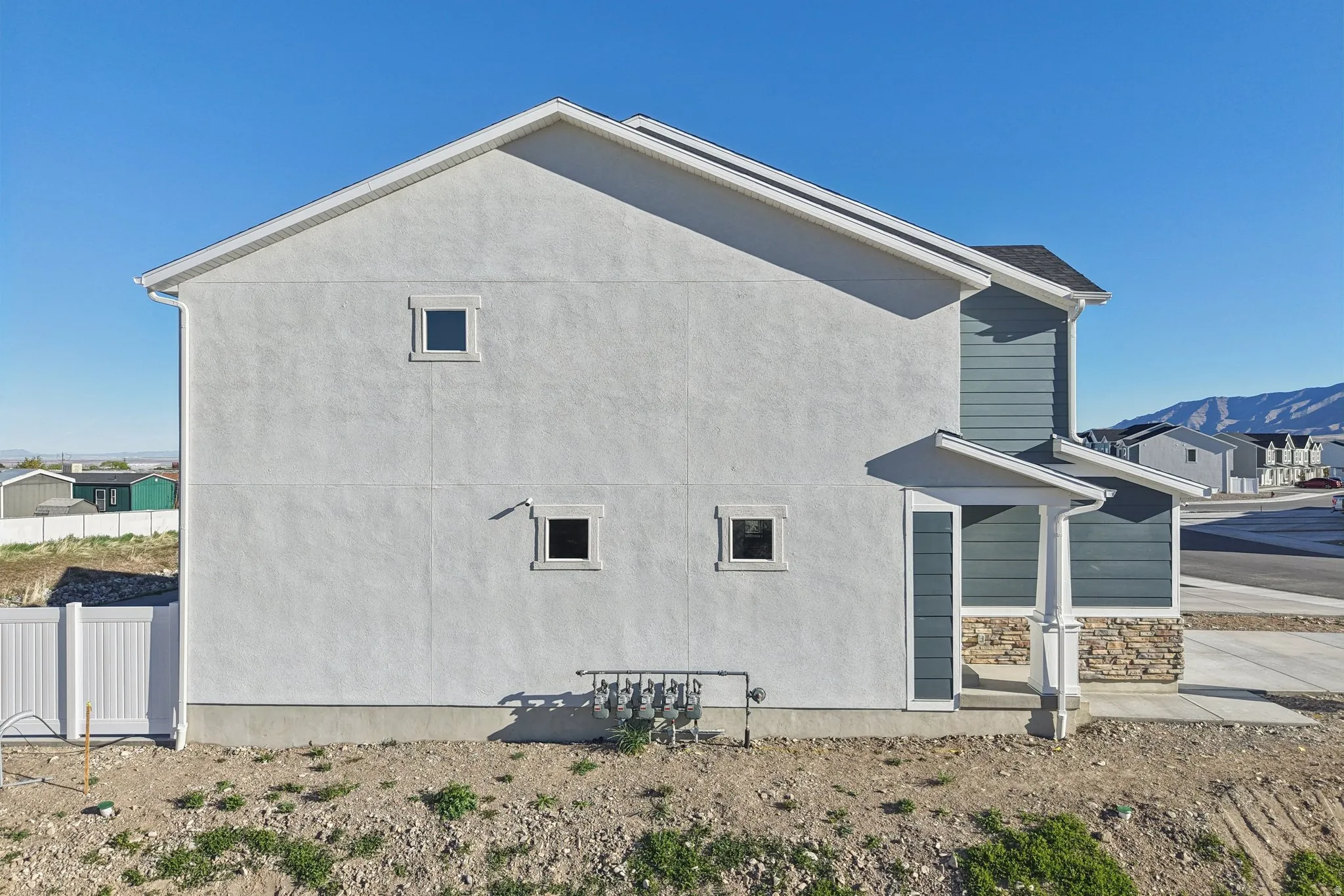 Stucco exterior with a pitched roof, featuring a covered entry, stone veneer accents, and horizontal siding