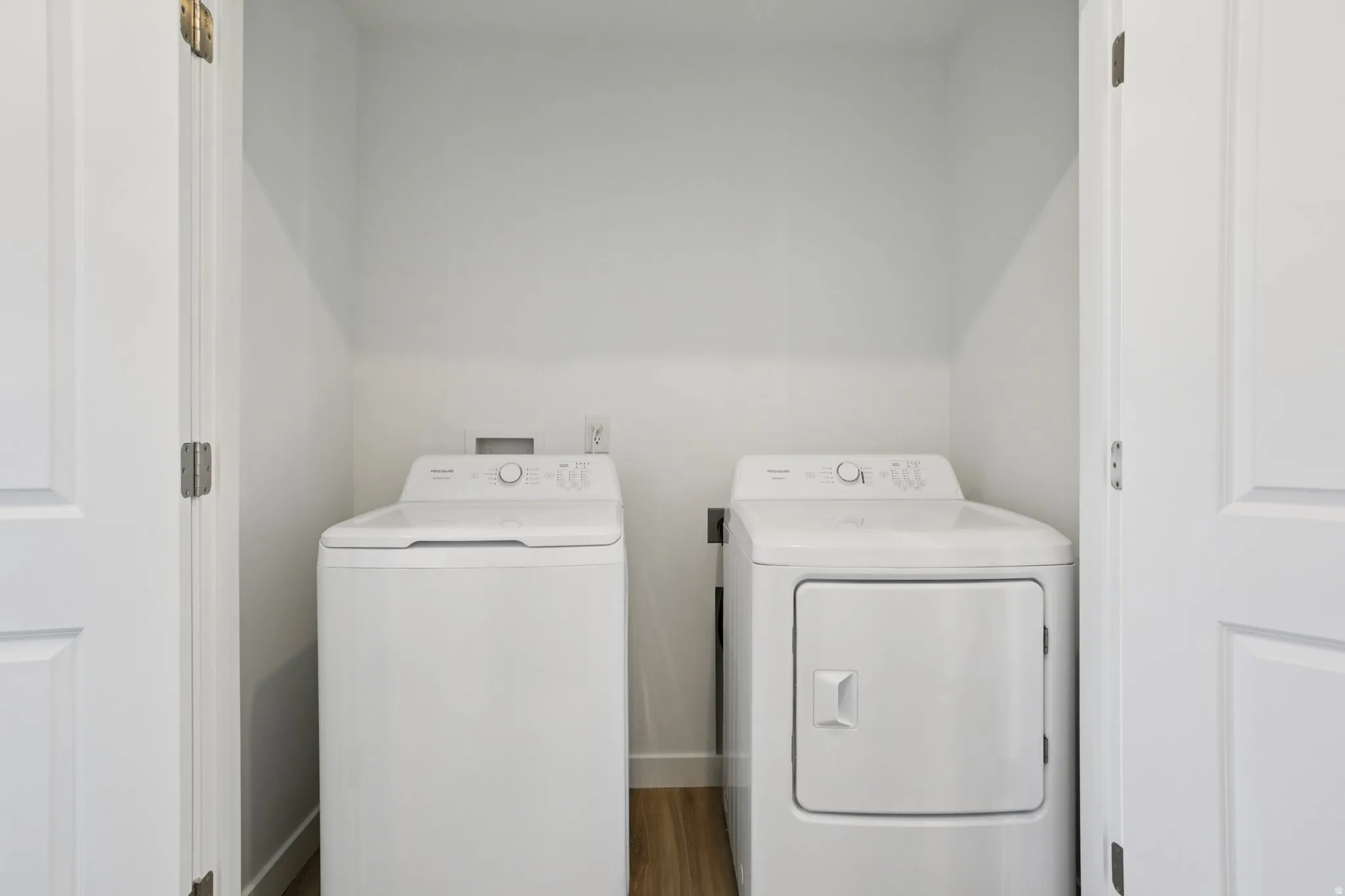 Enclosed utility area featuring a top-load washing machine and front-load dryer