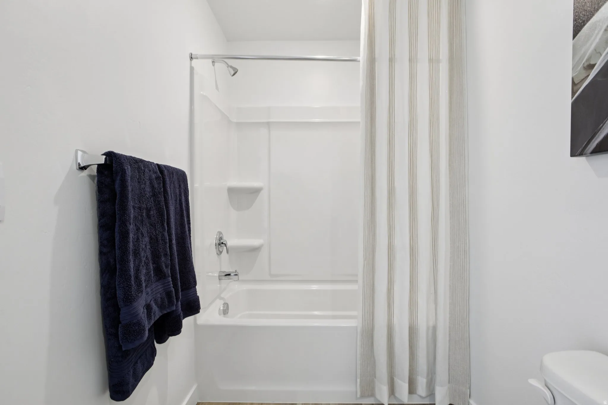 Bathtub with integrated shower, chrome fixtures, and a bright white surround