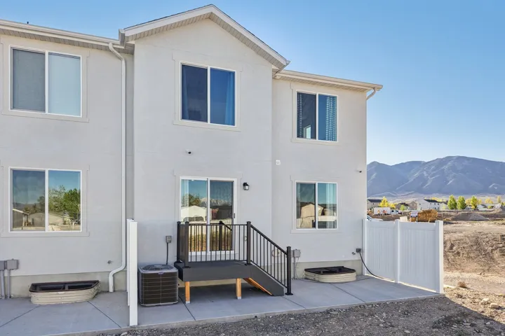 Modern two-story residence featuring a clean white exterior with multiple windows and dark-framed glazing