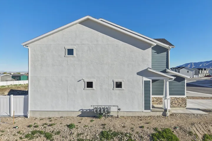 Stucco exterior with a pitched roof, featuring a covered entry, stone veneer accents, and horizontal siding