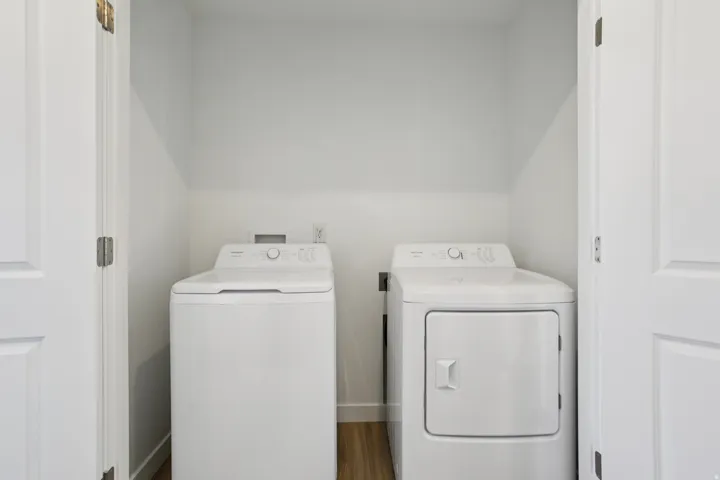Enclosed utility area featuring a top-load washing machine and front-load dryer