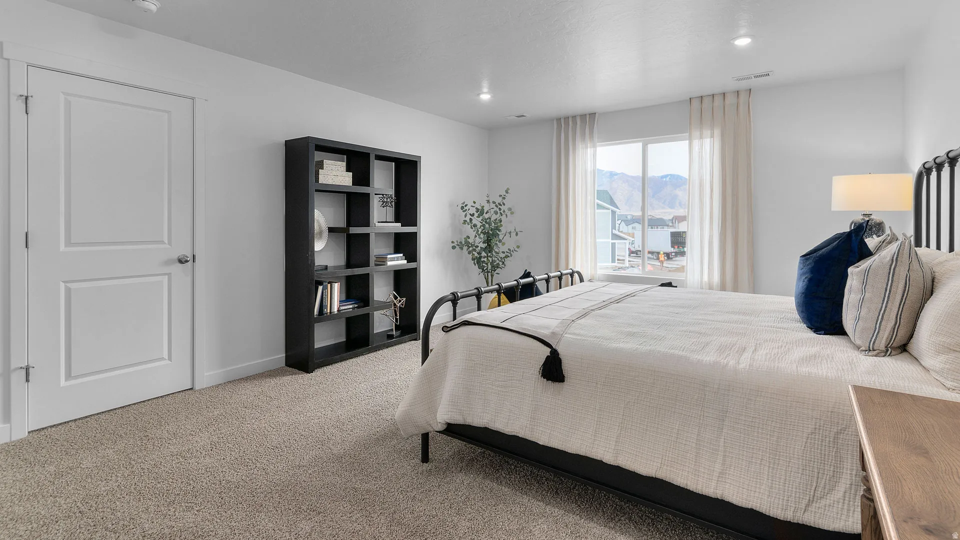 Recessed lighting, large window with mountain backdrop, neutral carpeting, and a two-panel interior door