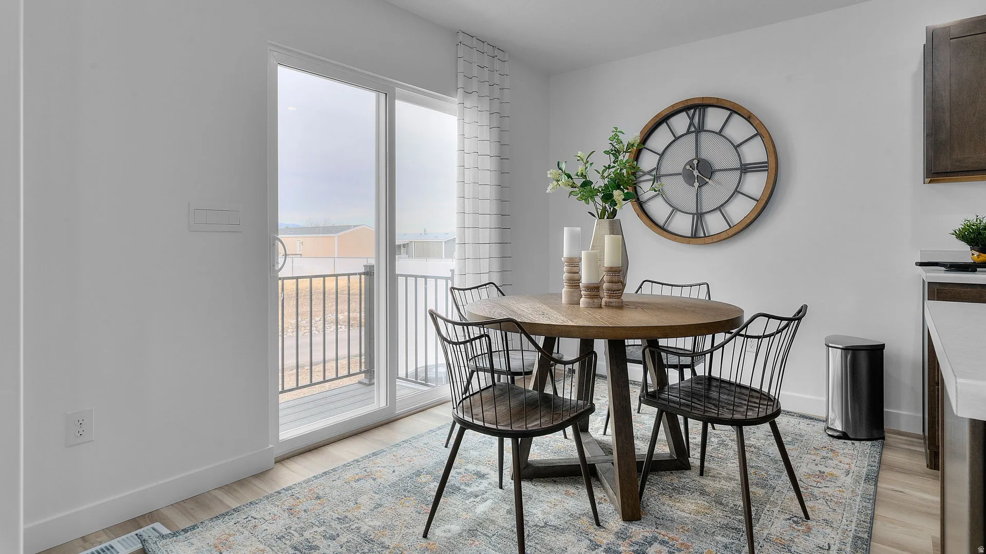 Sliding glass door to an outdoor balcony with metal railings, white walls, and wood-finish flooring