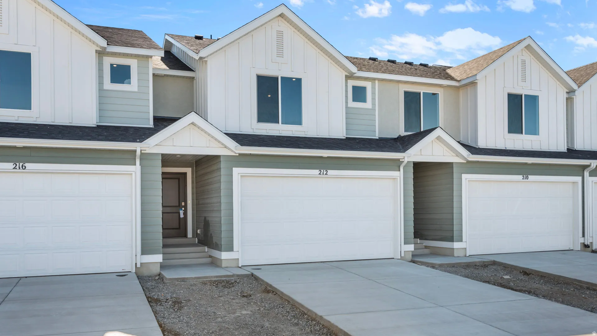 Modern townhome exterior featuring light green siding and white board-and-batten accents