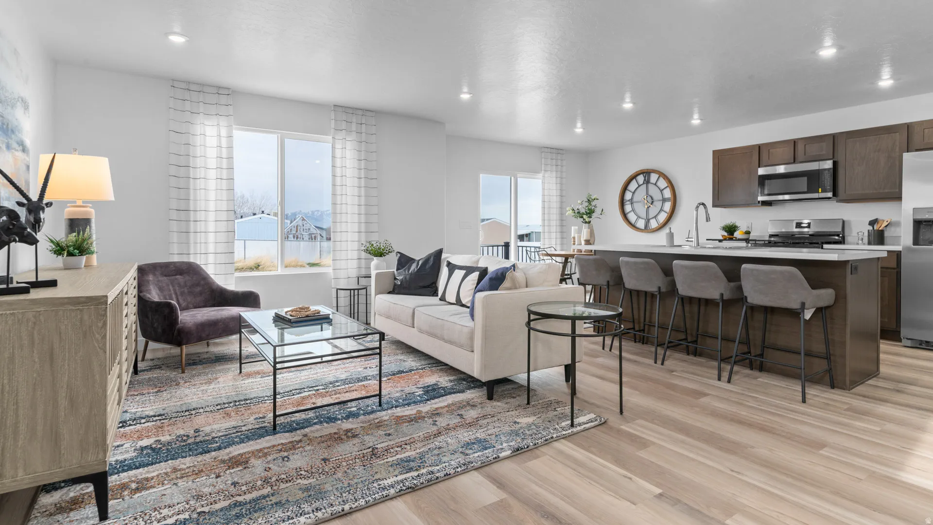 Open-concept living space featuring wood-finish flooring, recessed lighting, a kitchen island with seating, and stainless steel appliances