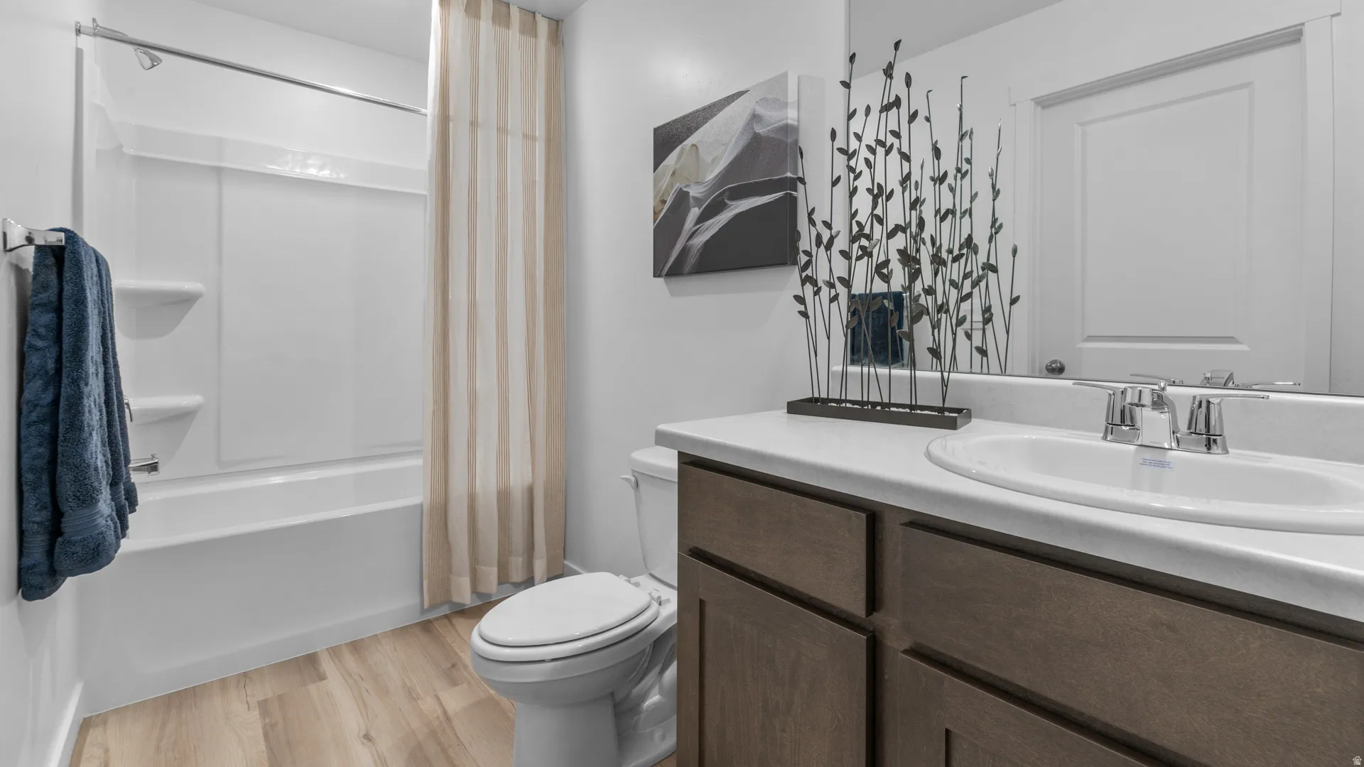 Bathroom featuring a wood-finish vanity with a white countertop, an integrated sink, and a chrome faucet