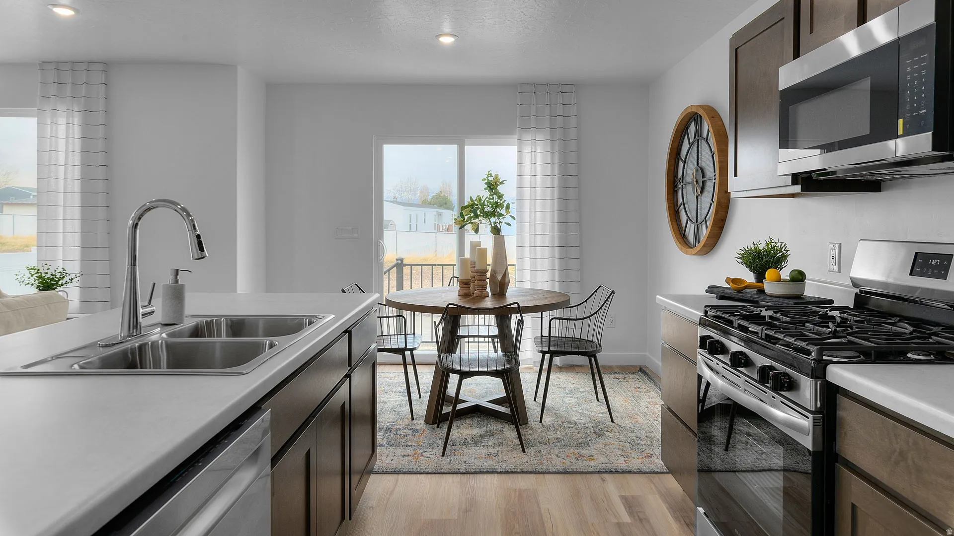 Stainless steel appliances, wood-finish flooring, dark wood-finish cabinetry, recessed lighting, and a stainless steel double basin sink
