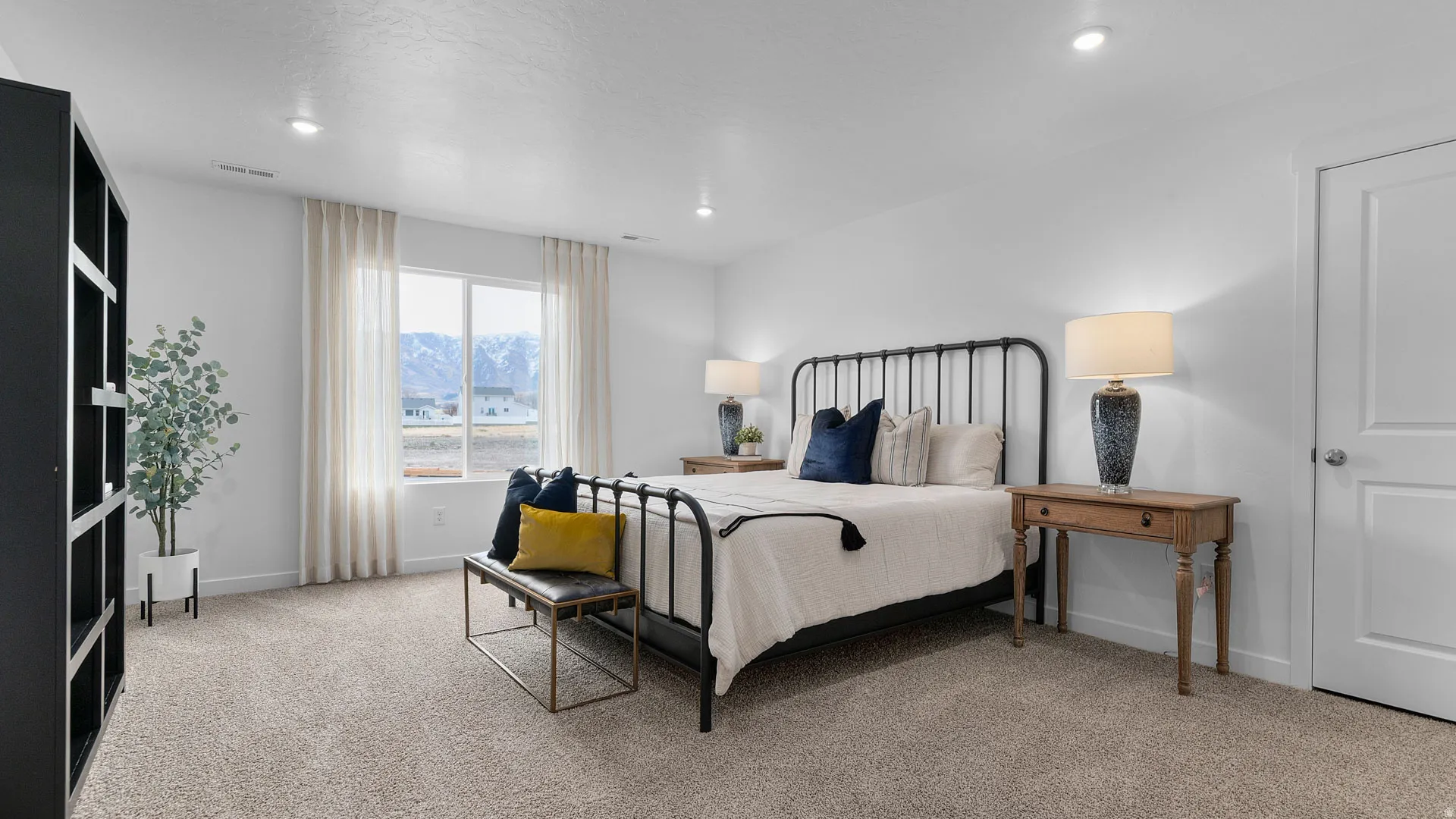 Recessed lighting, large window with mountain scenery, carpeted flooring, white interior doors, and built-in shelving