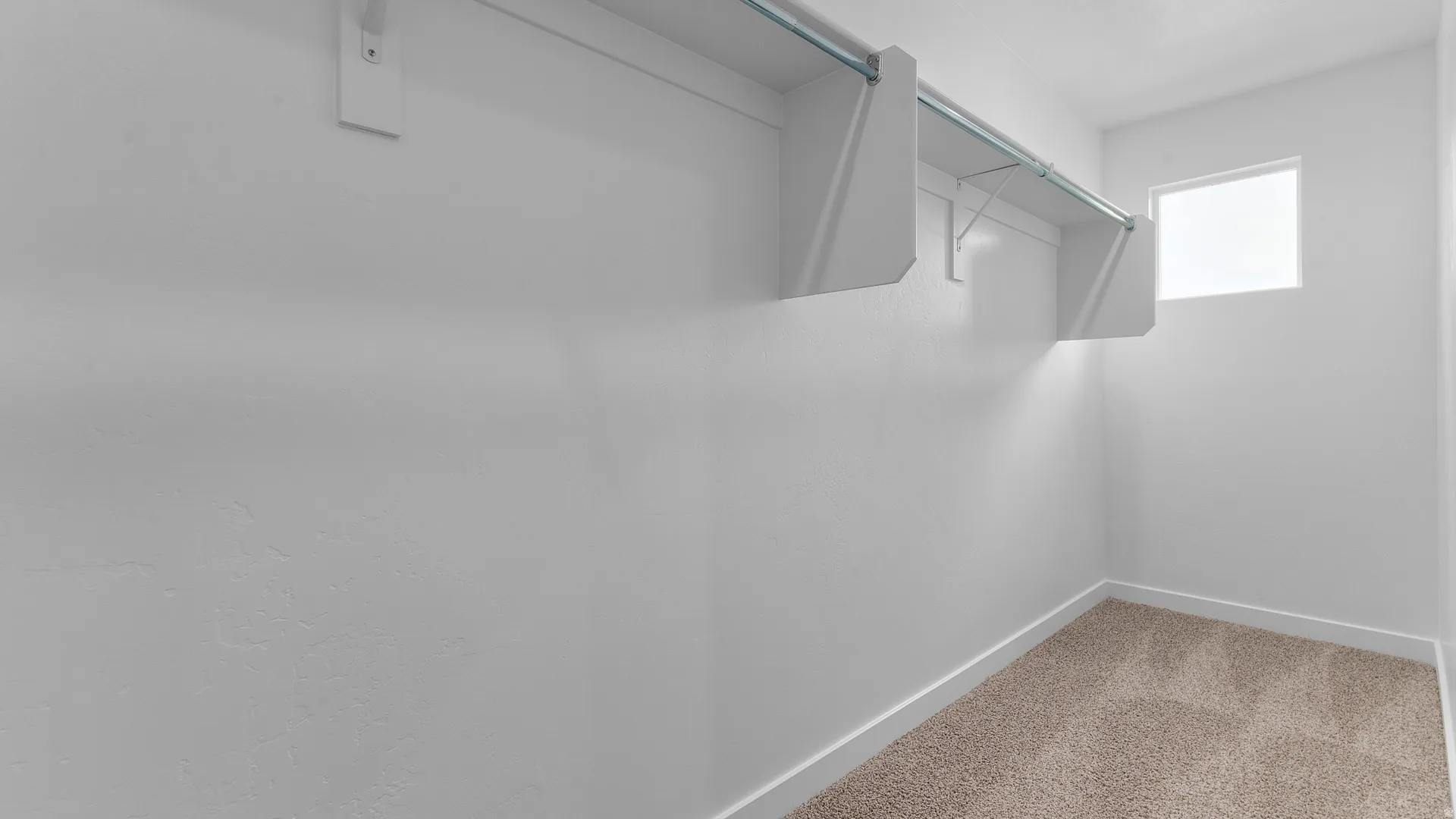 Built-in shelving with hanging rods, bright white walls, and a single window