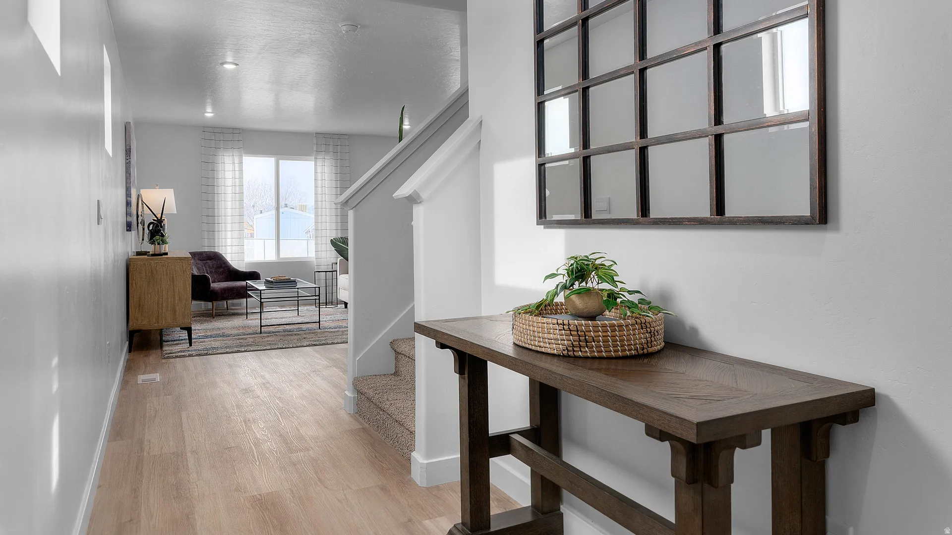 Wood-finish flooring extending into the main living area, staircase with carpeted treads, and recessed ceiling lighting