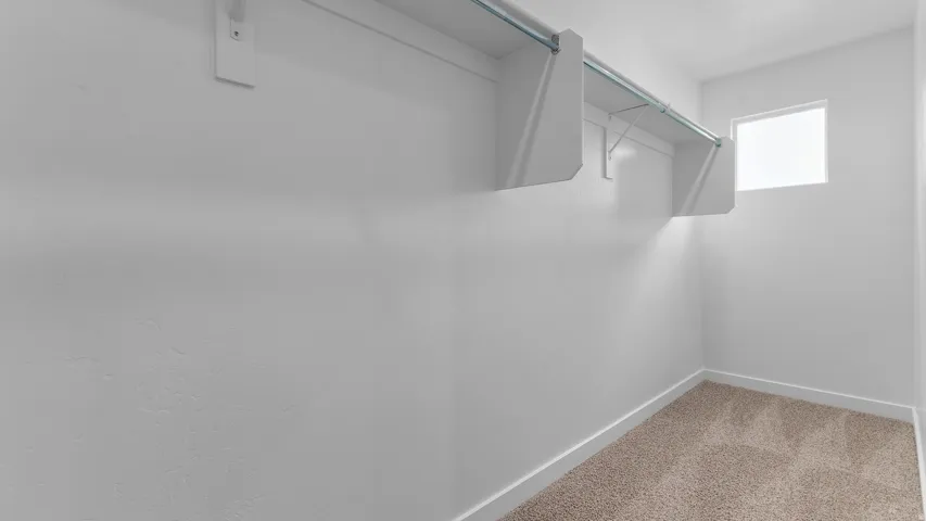 Built-in shelving with hanging rods, bright white walls, and a single window