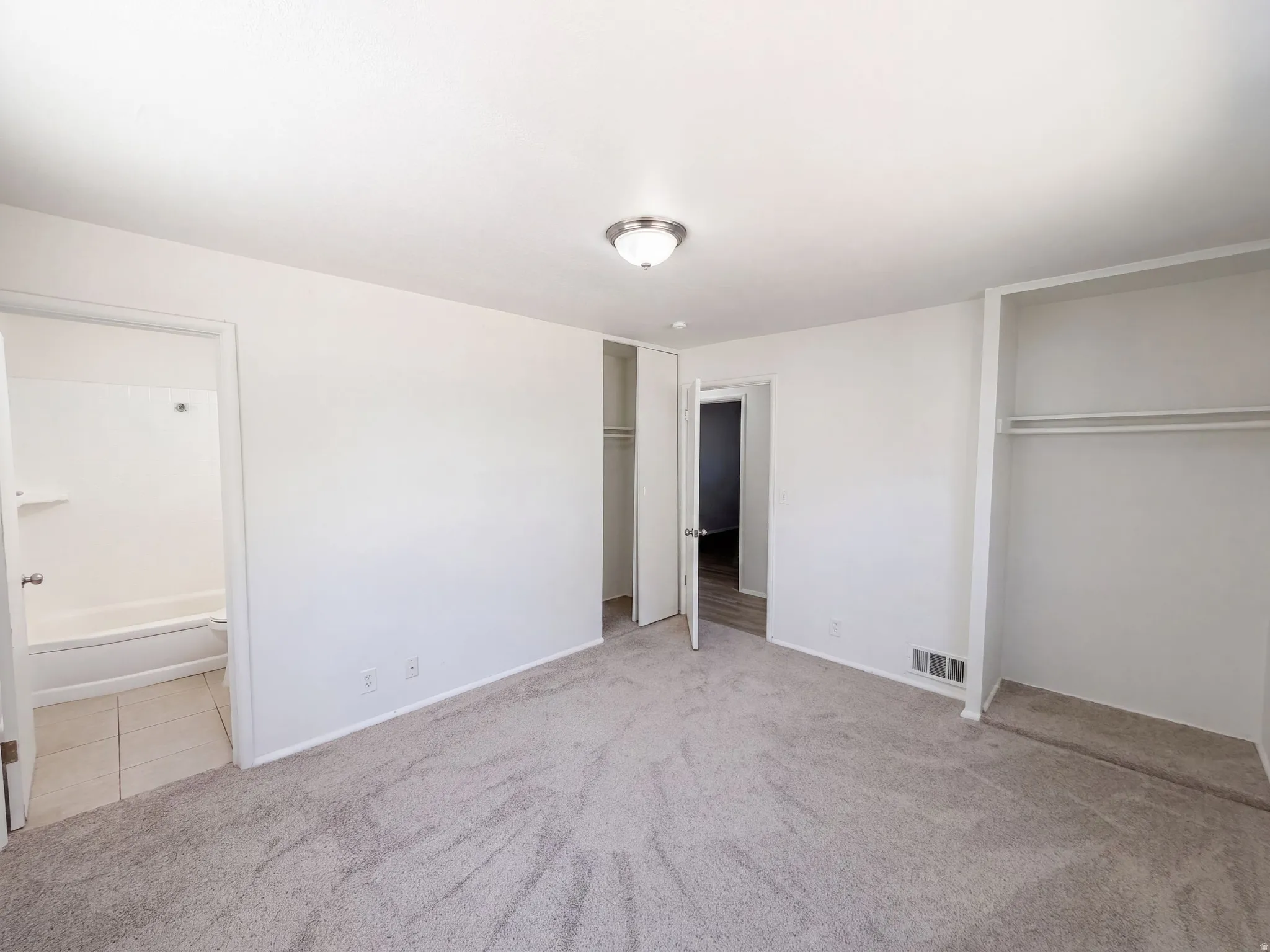 Plush carpeting, recessed closet, full bathroom with tiled flooring, and a flush mount ceiling light fixture
